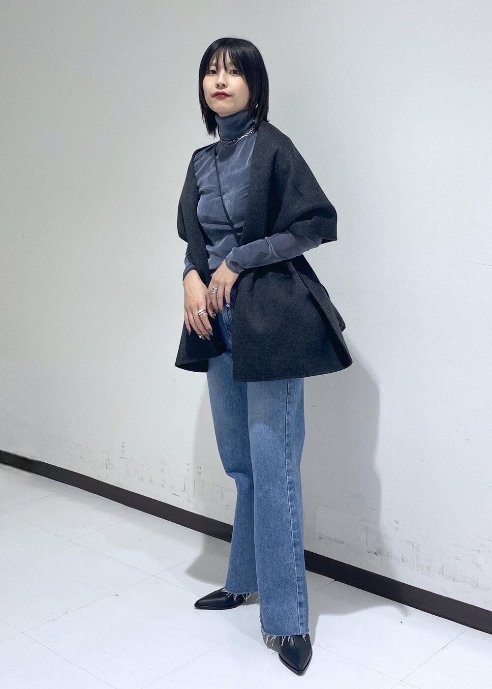 ブラック系のブーツ、ブルー系のデニムパンツ、ブラック系のハンドバッグを着用したレディースの秋コーディネートの2枚目の写真