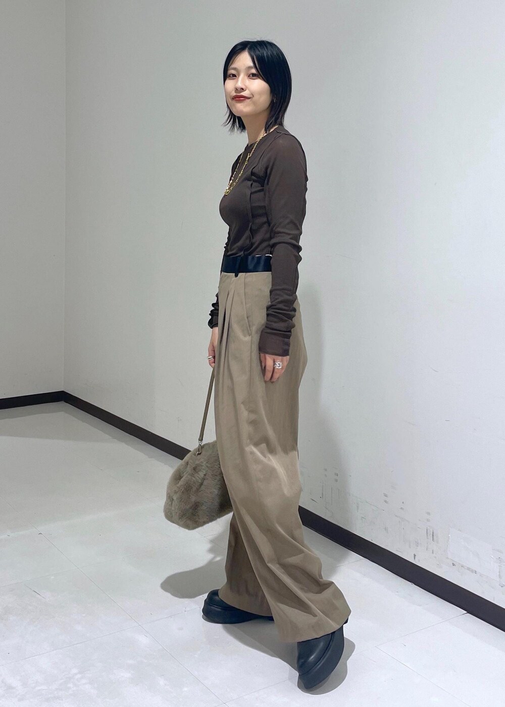 グリーン系のスラックス、ブラック系のサンダル、ブラウン系のTシャツ/カットソーを着用したレディースの秋コーディネートの2枚目の写真