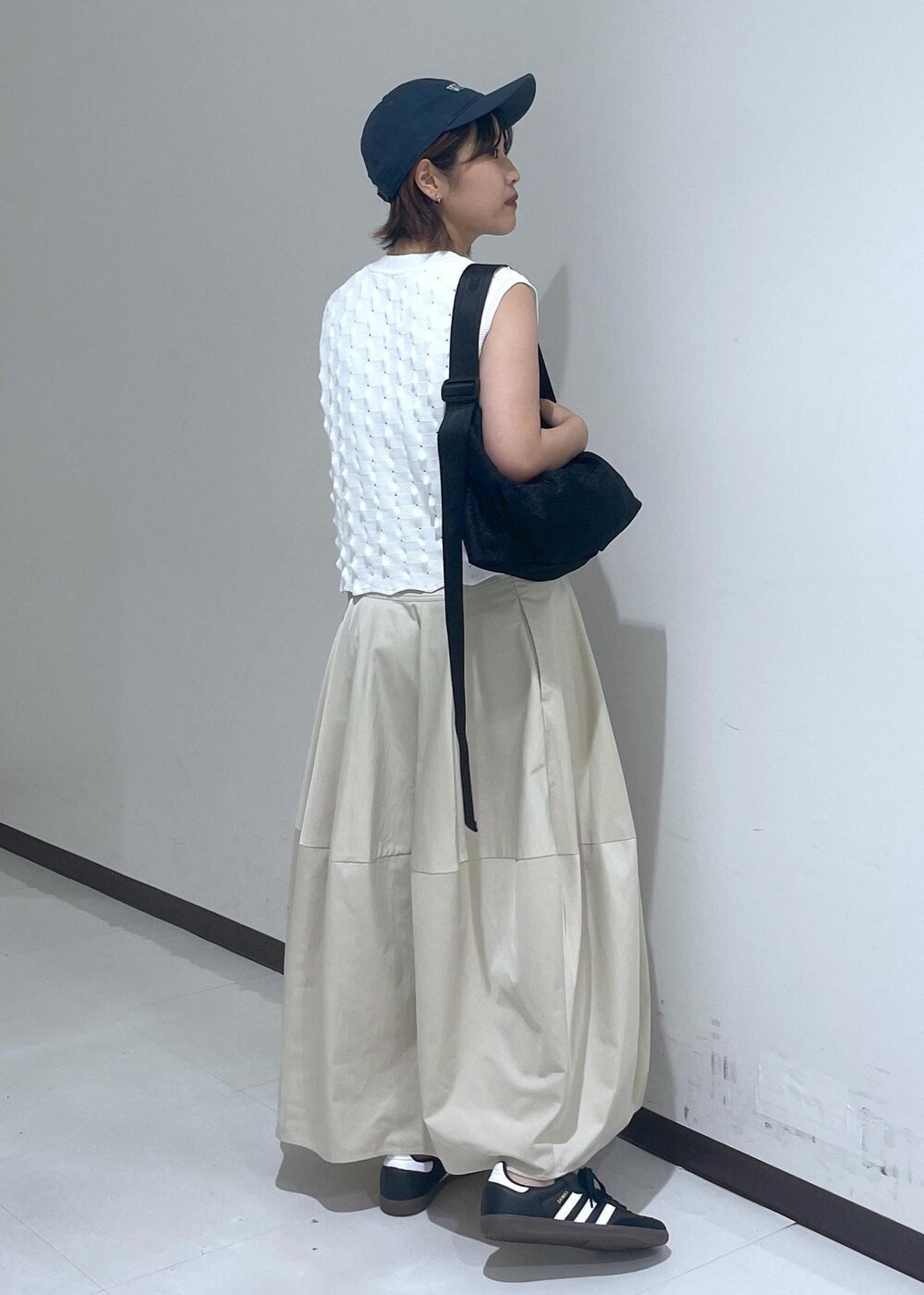 ベージュ系のスカート、ホワイト系のニット/セーター、ブルー系のキャップを着用したレディースの夏コーディネートの5枚目の写真
