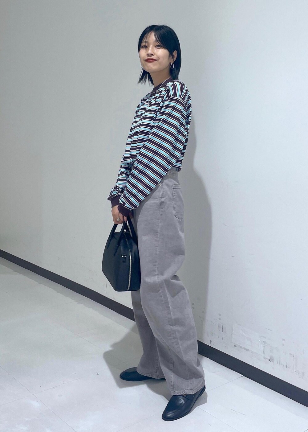 ブラック系のローファー、ブラック系のボストンバッグ、ベージュ系のデニムパンツを着用したレディースの秋コーディネートの2枚目の写真