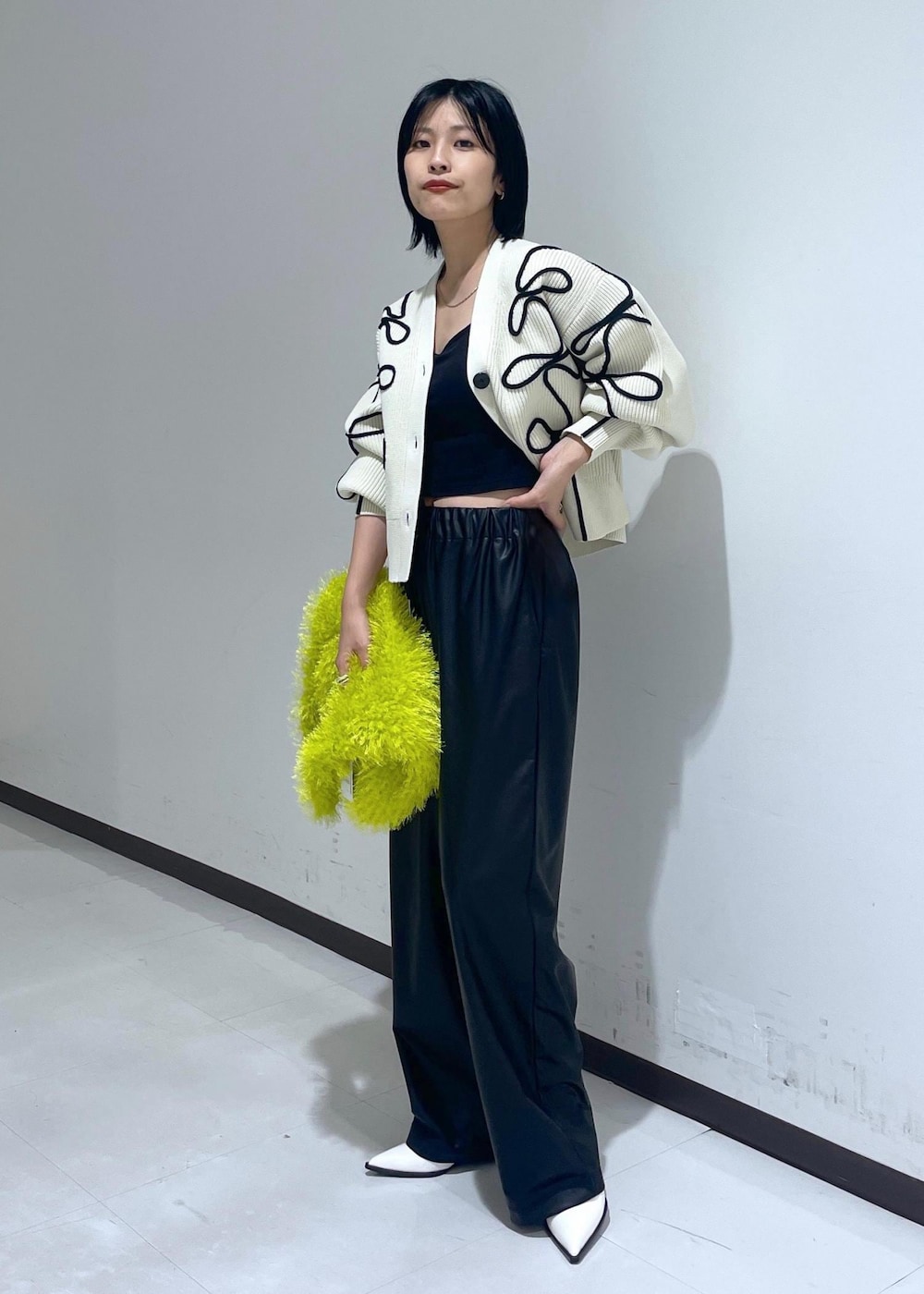 ホワイト系のパンプス、ホワイト系のカーディガン/ボレロ、グリーン系のハンドバッグを着用したレディースの秋コーディネートの2枚目の写真