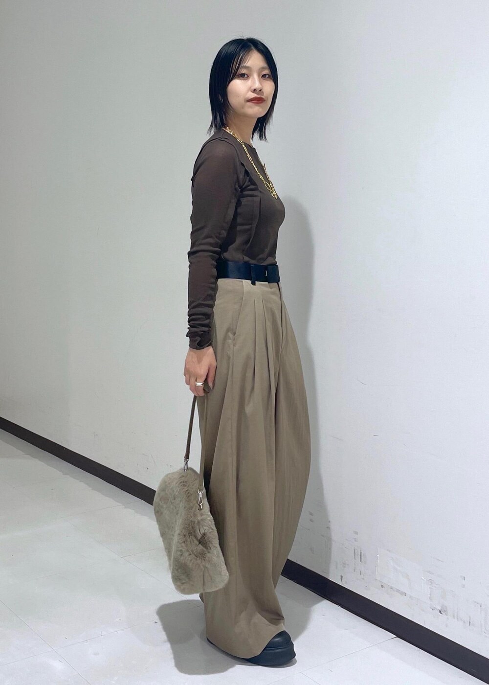 グリーン系のスラックス、ブラック系のサンダル、ブラウン系のTシャツ/カットソーを着用したレディースの秋コーディネートの4枚目の写真