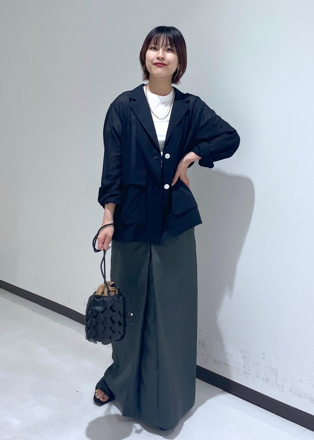 グレー系のスカート、ブラック系のテーラードジャケット、ホワイト系のTシャツ/カットソーを着用したレディースの夏コーディネートの5枚目の写真