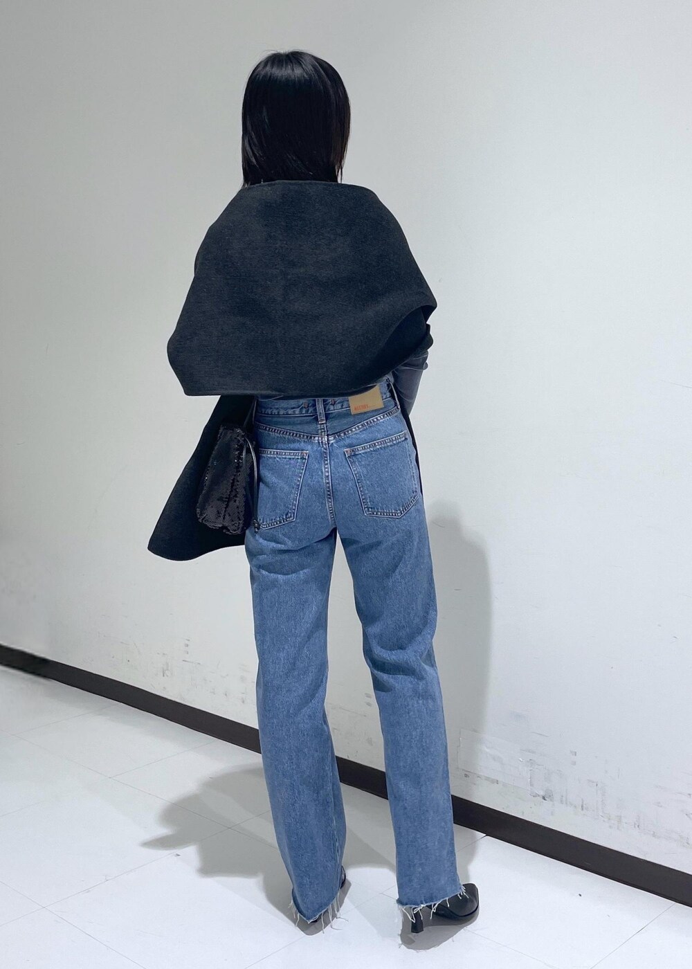 ブラック系のブーツ、ブルー系のデニムパンツ、ブラック系のハンドバッグを着用したレディースの秋コーディネートの3枚目の写真