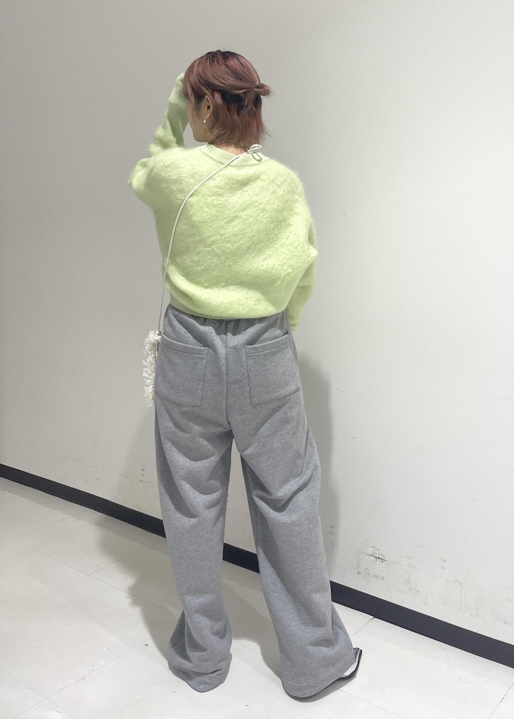 シルバー系のパンプス、グリーン系のニット/セーター、ホワイト系のショルダーバッグを着用したレディースの秋コーディネートの2枚目の写真