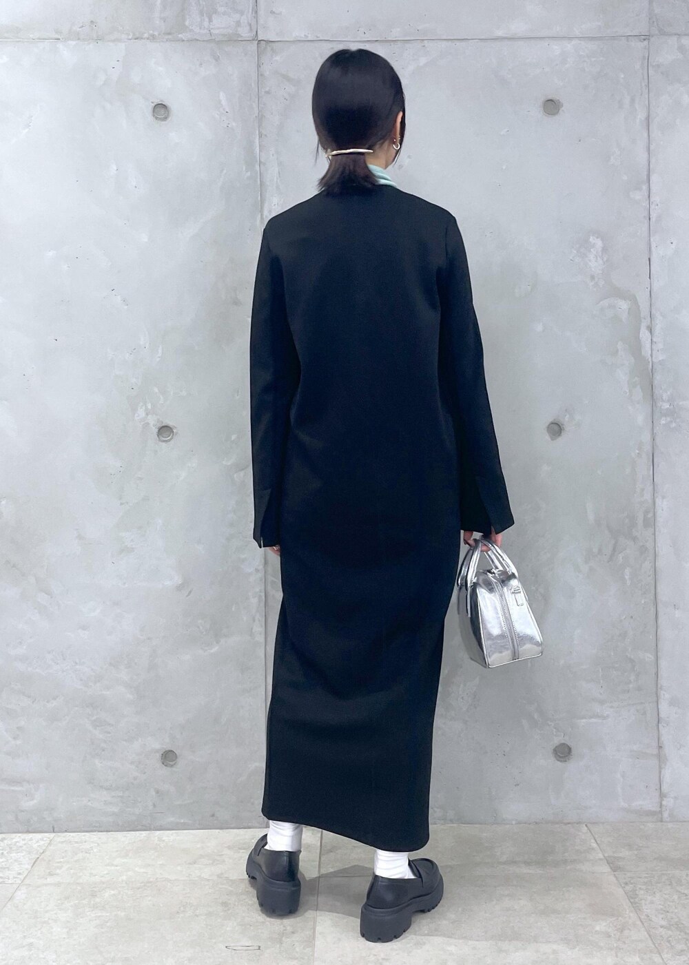 ブラック系のローファー、グリーン系のニット/セーター、シルバー系のショルダーバッグを着用したレディースの冬コーディネートの6枚目の写真