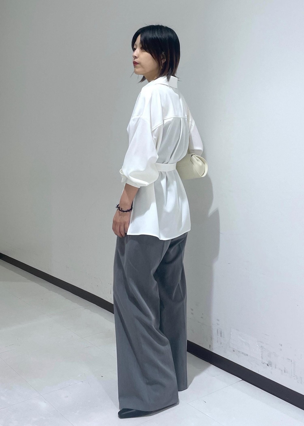 ホワイト系のシャツ/ブラウス、ホワイト系のショルダーバッグ、グレー系のスラックスを着用したレディースの夏コーディネートの3枚目の写真