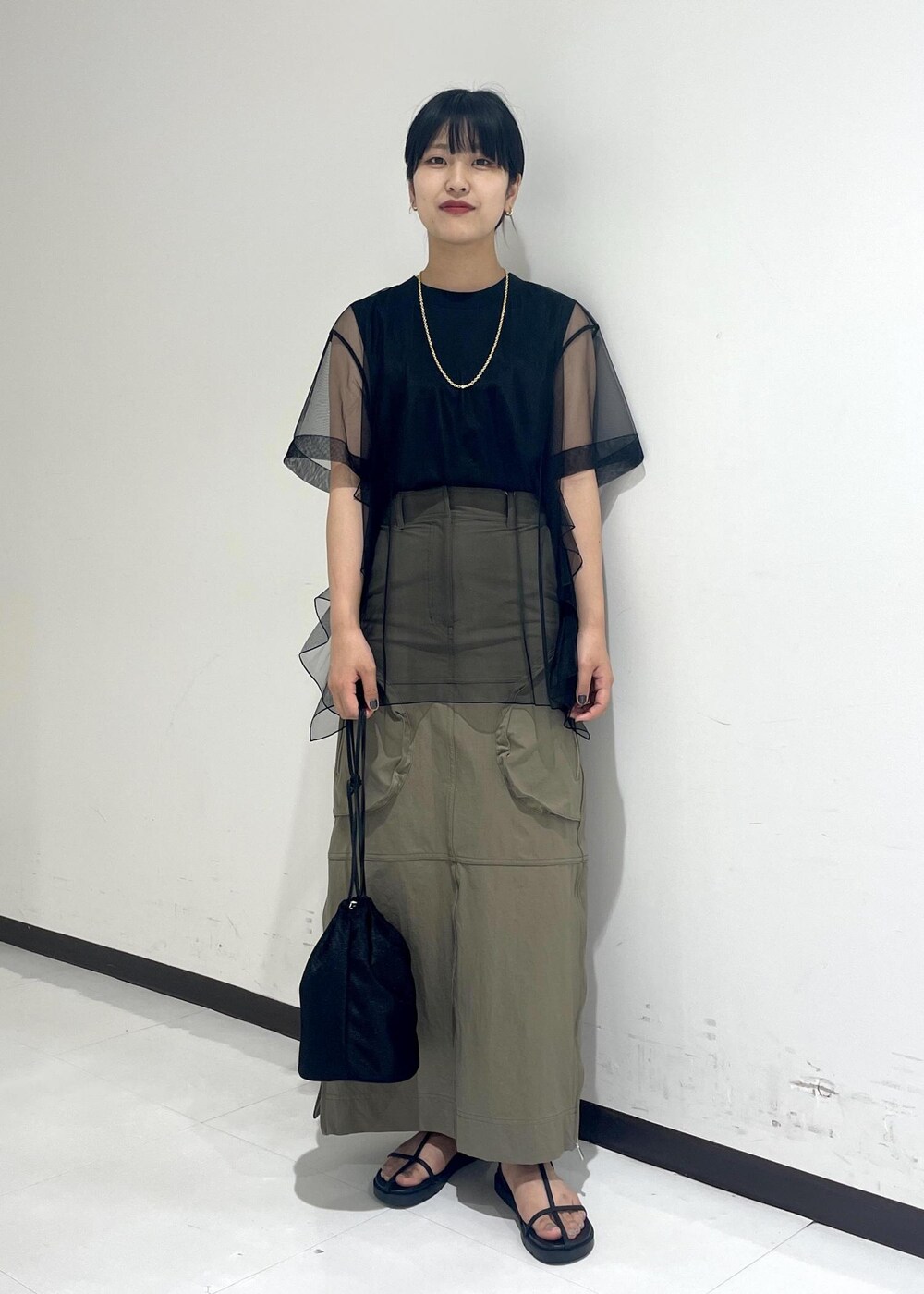 ブラック系のサンダル、ブラック系のショルダーバッグ、ベージュ系のスカートを着用したレディースの夏コーディネートの2枚目の写真