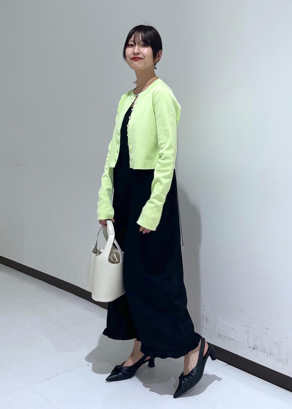 ブラック系のパンプス、ブラック系のワンピース、グリーン系のカーディガン/ボレロを着用したレディースの春コーディネートの2枚目の写真