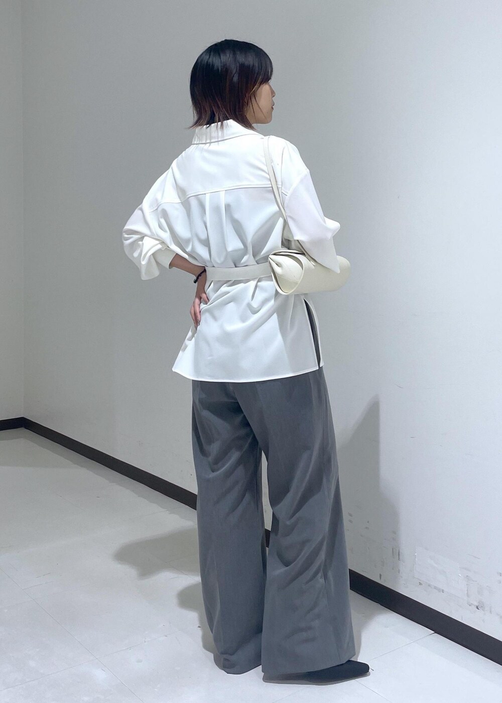 ホワイト系のシャツ/ブラウス、ホワイト系のショルダーバッグ、グレー系のスラックスを着用したレディースの夏コーディネートの5枚目の写真