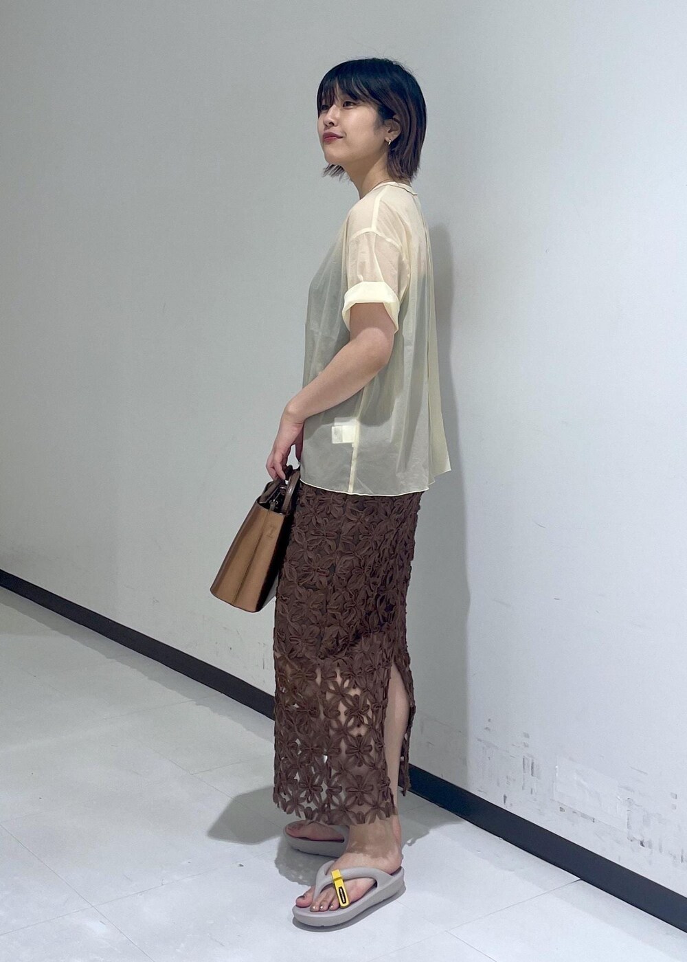 グレー系のサンダル、ベージュ系のTシャツ/カットソー、その他のハンドバッグを着用したレディースの夏コーディネートの2枚目の写真