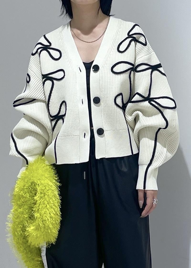 ホワイト系のパンプス、ホワイト系のカーディガン/ボレロ、グリーン系のハンドバッグを着用したレディースの秋コーディネートの6枚目の写真