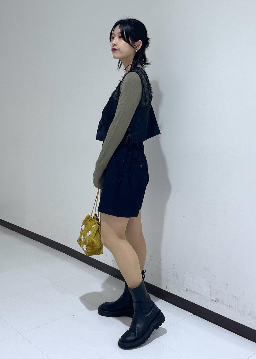 ブラック系のブーツ、グリーン系のニット/セーター、イエロー系のハンドバッグを着用したレディースの秋コーディネートの2枚目の写真