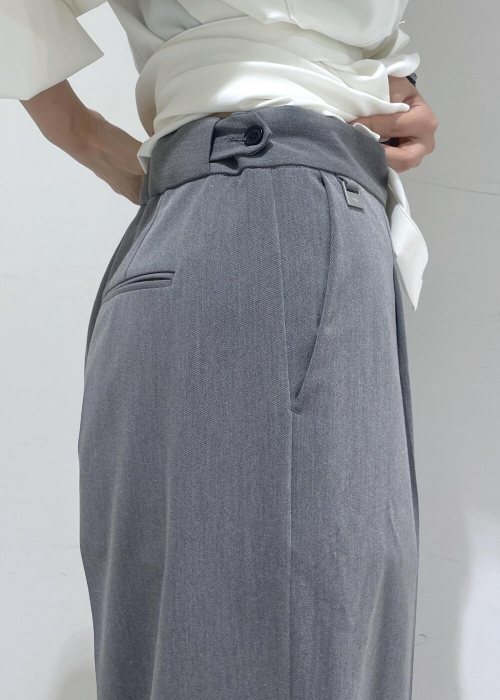 ホワイト系のシャツ/ブラウス、ホワイト系のショルダーバッグ、グレー系のスラックスを着用したレディースの夏コーディネートの10枚目の写真