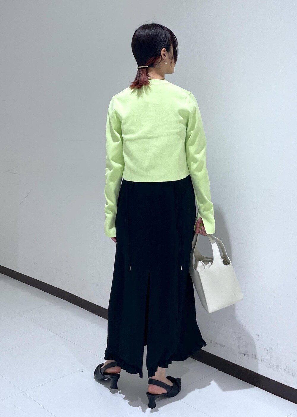 ブラック系のパンプス、ブラック系のワンピース、グリーン系のカーディガン/ボレロを着用したレディースの春コーディネートの3枚目の写真