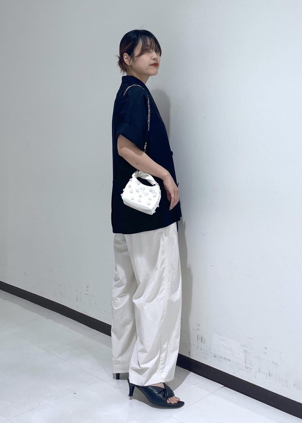 ブラック系のサンダル、ホワイト系のショルダーバッグ、ブラック系のテーラードジャケットを着用したレディースの春コーディネートの4枚目の写真