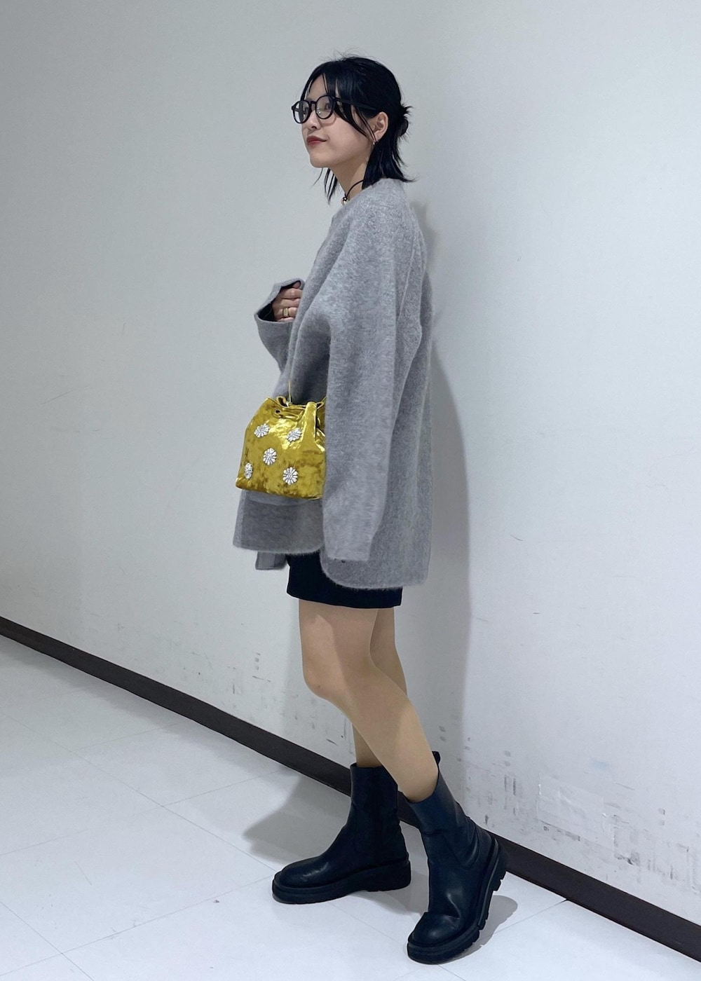 ブラック系のブーツ、グリーン系のニット/セーター、イエロー系のハンドバッグを着用したレディースの秋コーディネートの2枚目の写真