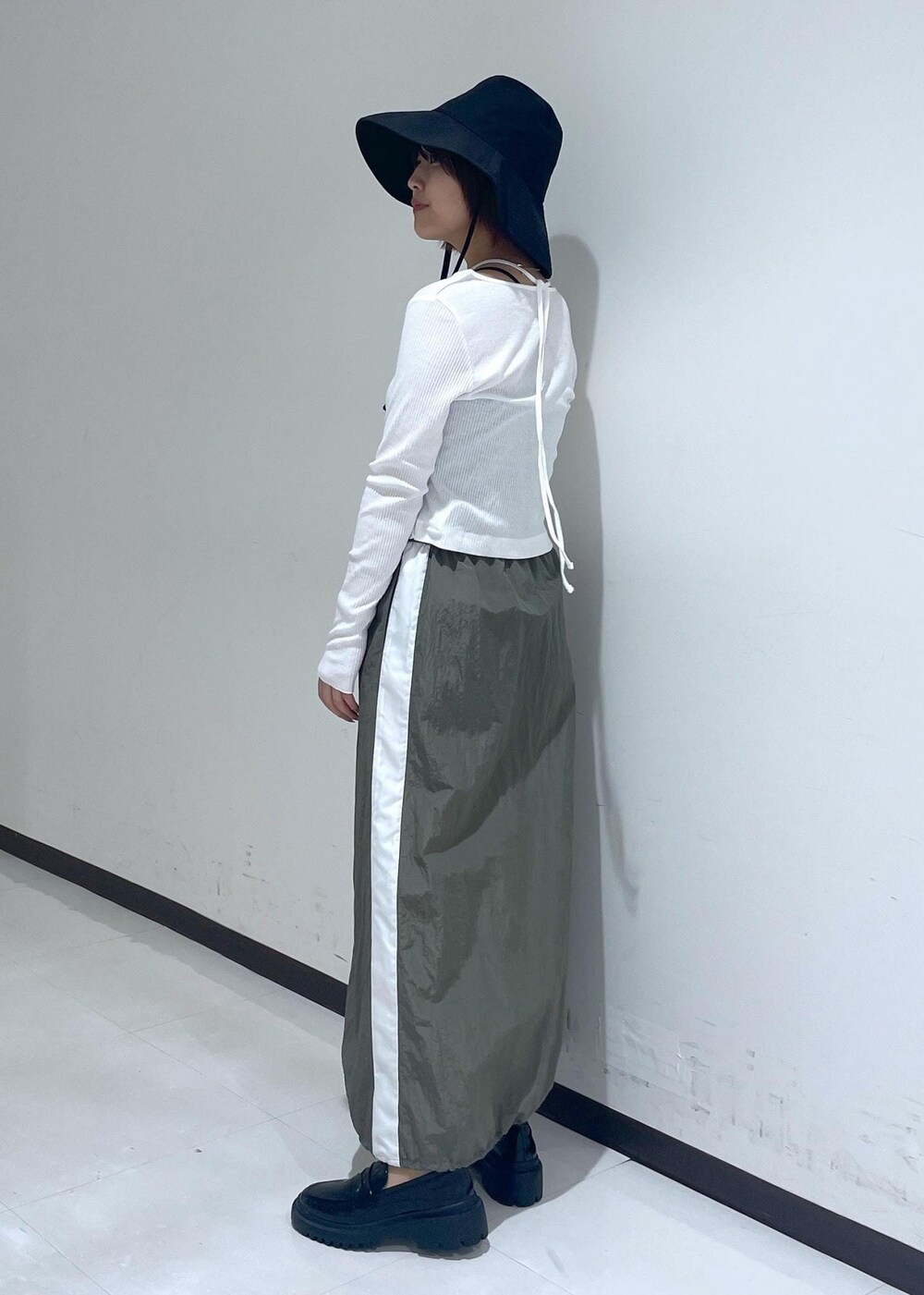 ブラック系のローファー、グリーン系のスカート、ホワイト系のカーディガン/ボレロを着用したレディースの春コーディネートの2枚目の写真