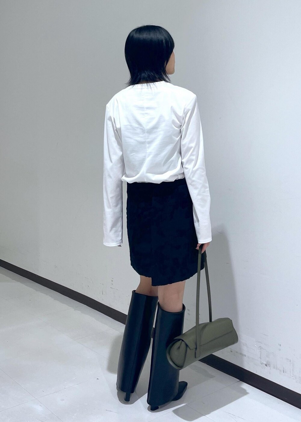 ブラック系のスカート、ブラック系のブーツ、ホワイト系のTシャツ/カットソーを着用したレディースの秋コーディネートの5枚目の写真