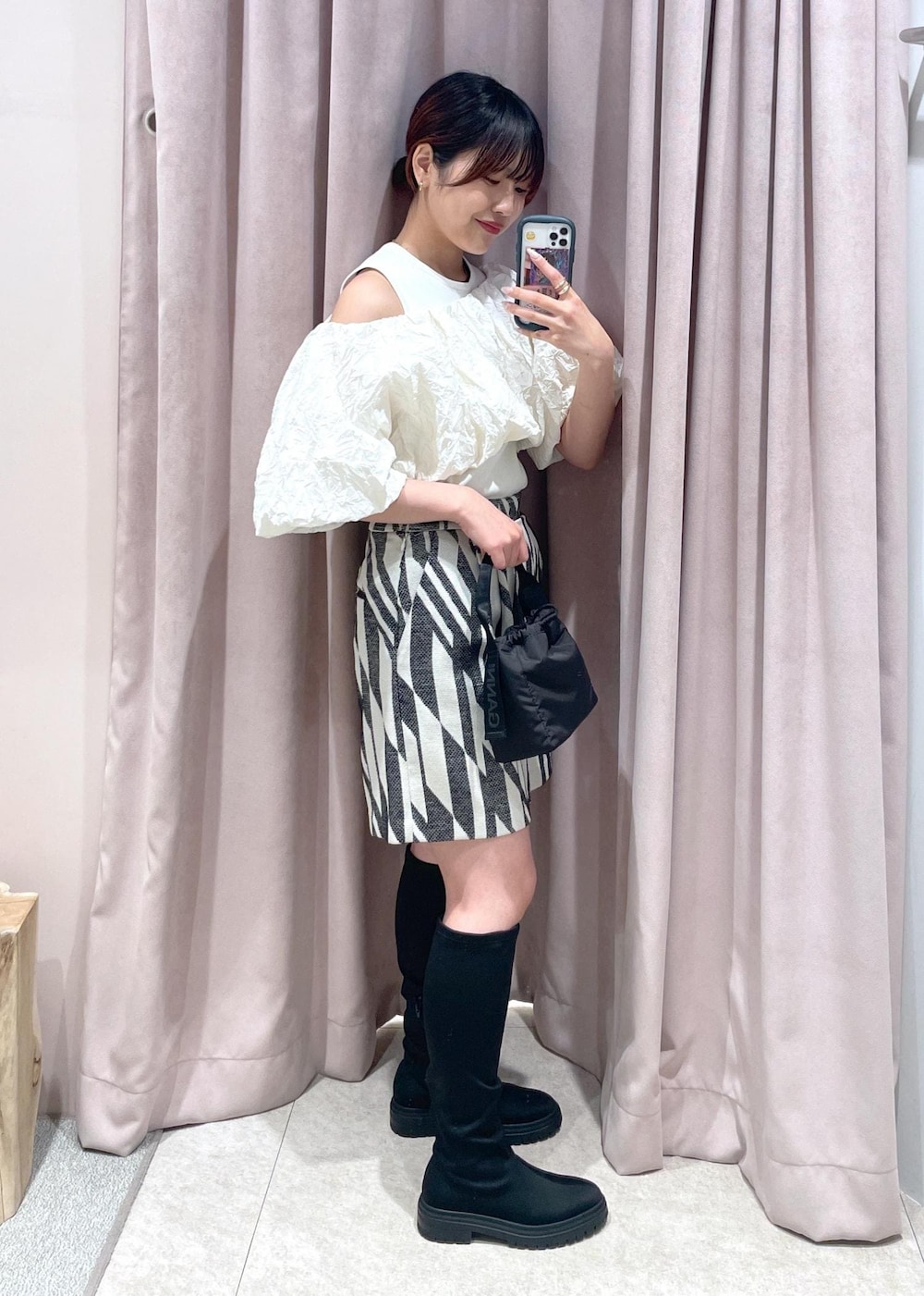 ブラック系のブーツ、ブラック系のハンドバッグ、ホワイト系のその他トップスを着用したレディースの春コーディネートの2枚目の写真