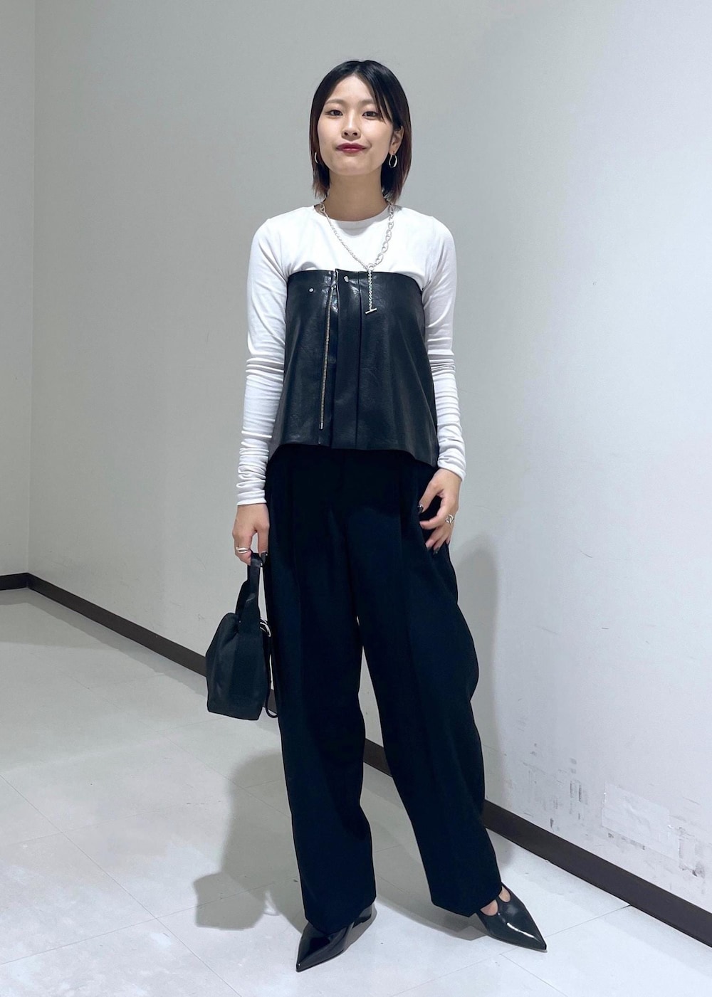 ブラック系のハンドバッグ、グレー系のTシャツ/カットソー、ブラック系のパンプスを着用したレディースの夏コーディネートの2枚目の写真