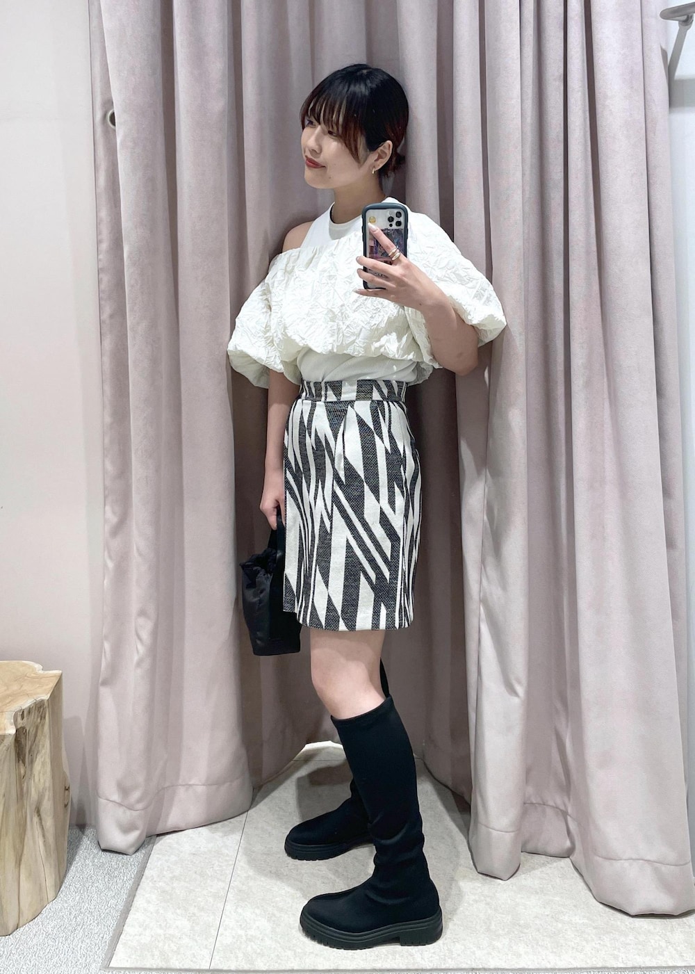 ブラック系のブーツ、ブラック系のハンドバッグ、ホワイト系のその他トップスを着用したレディースの春コーディネートの3枚目の写真