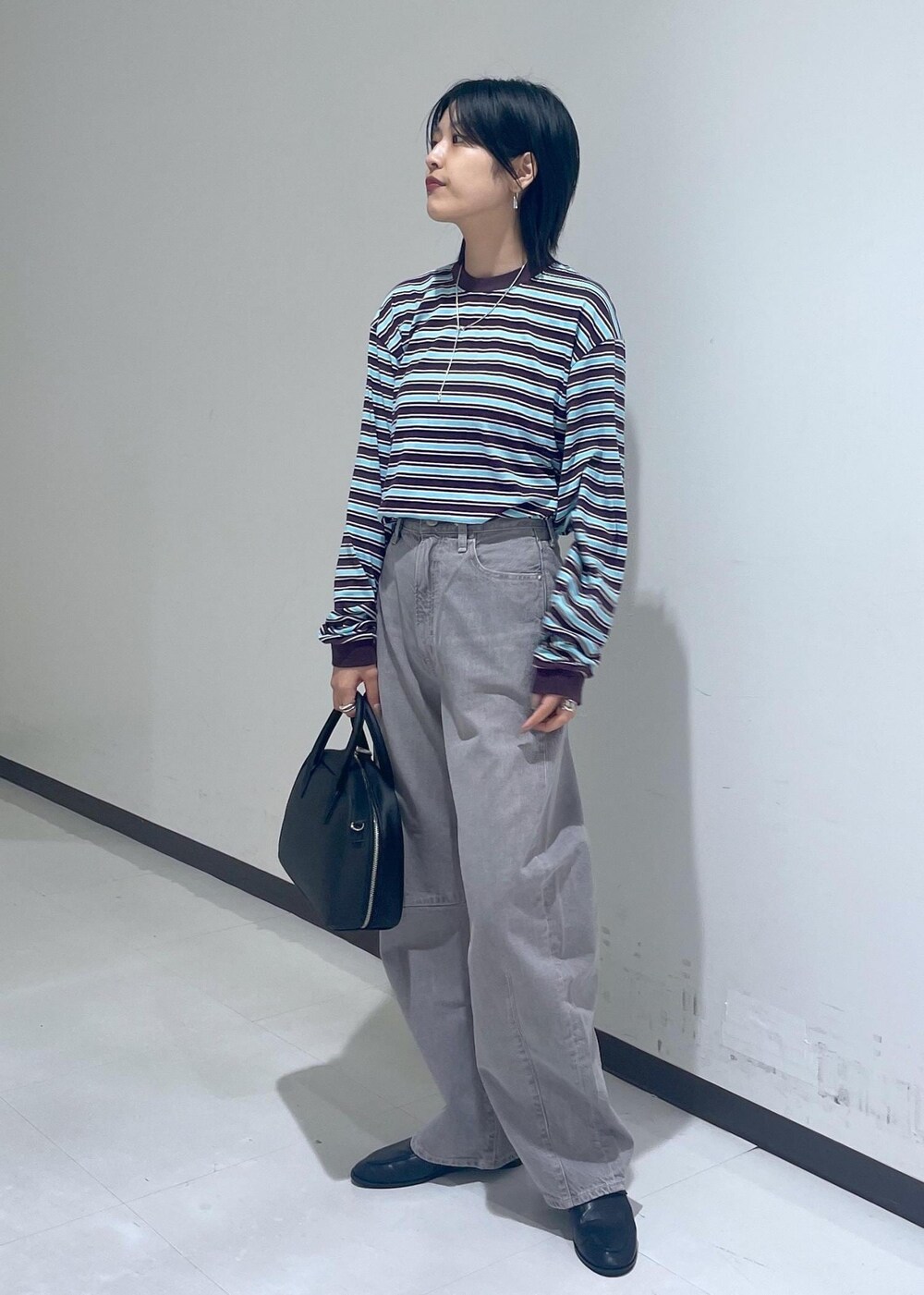 ブラック系のローファー、ブラック系のボストンバッグ、ベージュ系のデニムパンツを着用したレディースの秋コーディネートの3枚目の写真