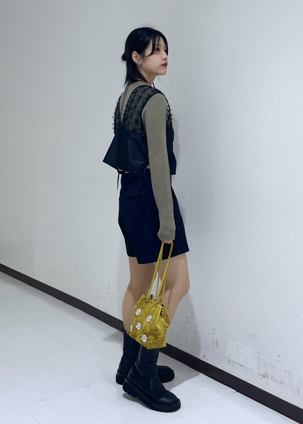 ブラック系のブーツ、グリーン系のニット/セーター、イエロー系のハンドバッグを着用したレディースの秋コーディネートの4枚目の写真