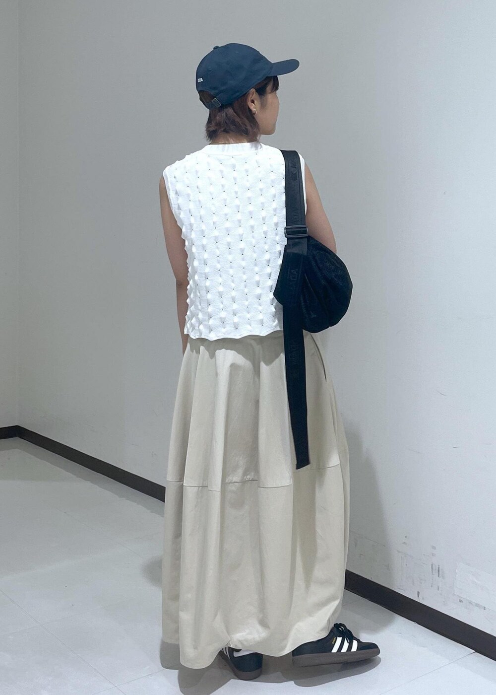 ベージュ系のスカート、ホワイト系のニット/セーター、ブルー系のキャップを着用したレディースの夏コーディネートの4枚目の写真