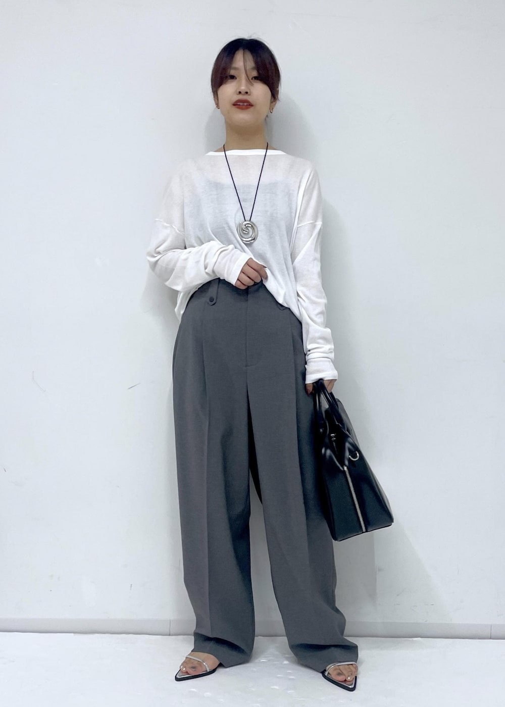 ブラック系のボストンバッグ、シルバー系のサンダル、ホワイト系のTシャツ/カットソーを着用したレディースの春コーディネートの2枚目の写真