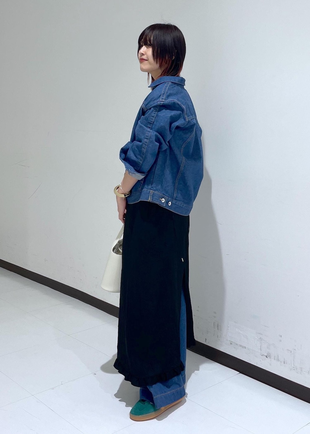 グリーン系のスニーカー、ブラック系のワンピース、ブルー系のブルゾンを着用したレディースの春コーディネートの2枚目の写真