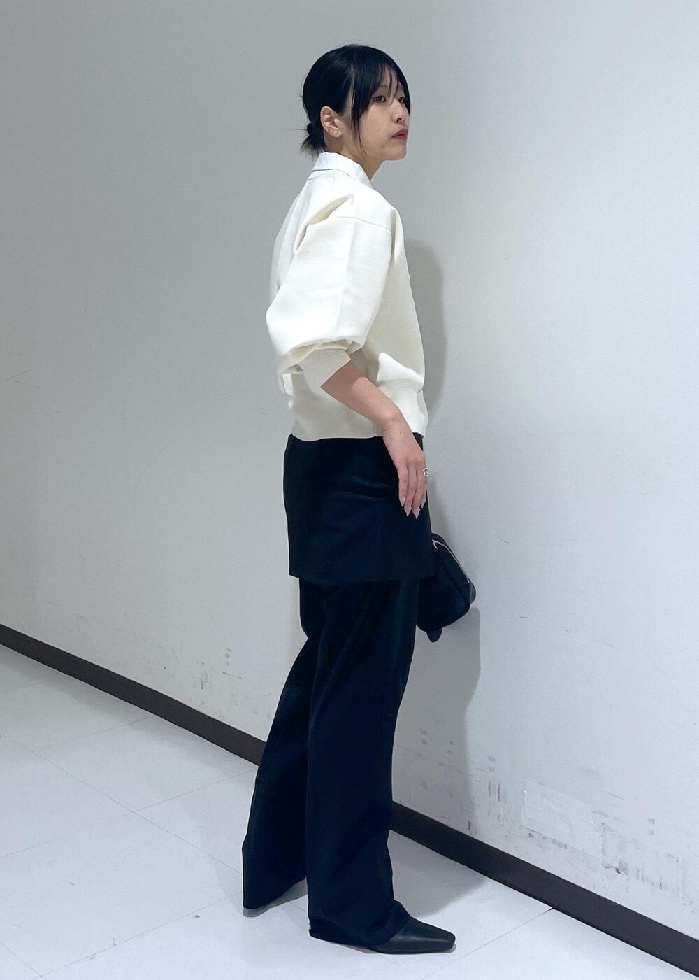 ブラック系のブーツ、ブラック系のスラックス、ブラック系のショルダーバッグを着用したレディースの冬コーディネートの4枚目の写真