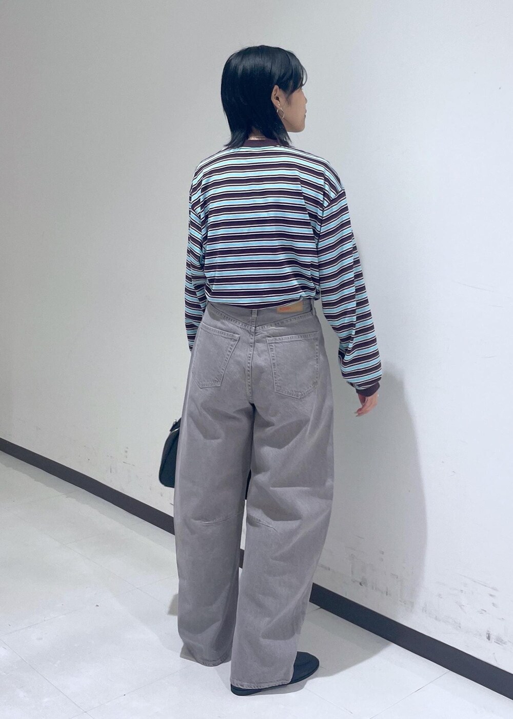 ブラック系のローファー、ブラック系のボストンバッグ、ベージュ系のデニムパンツを着用したレディースの秋コーディネートの6枚目の写真