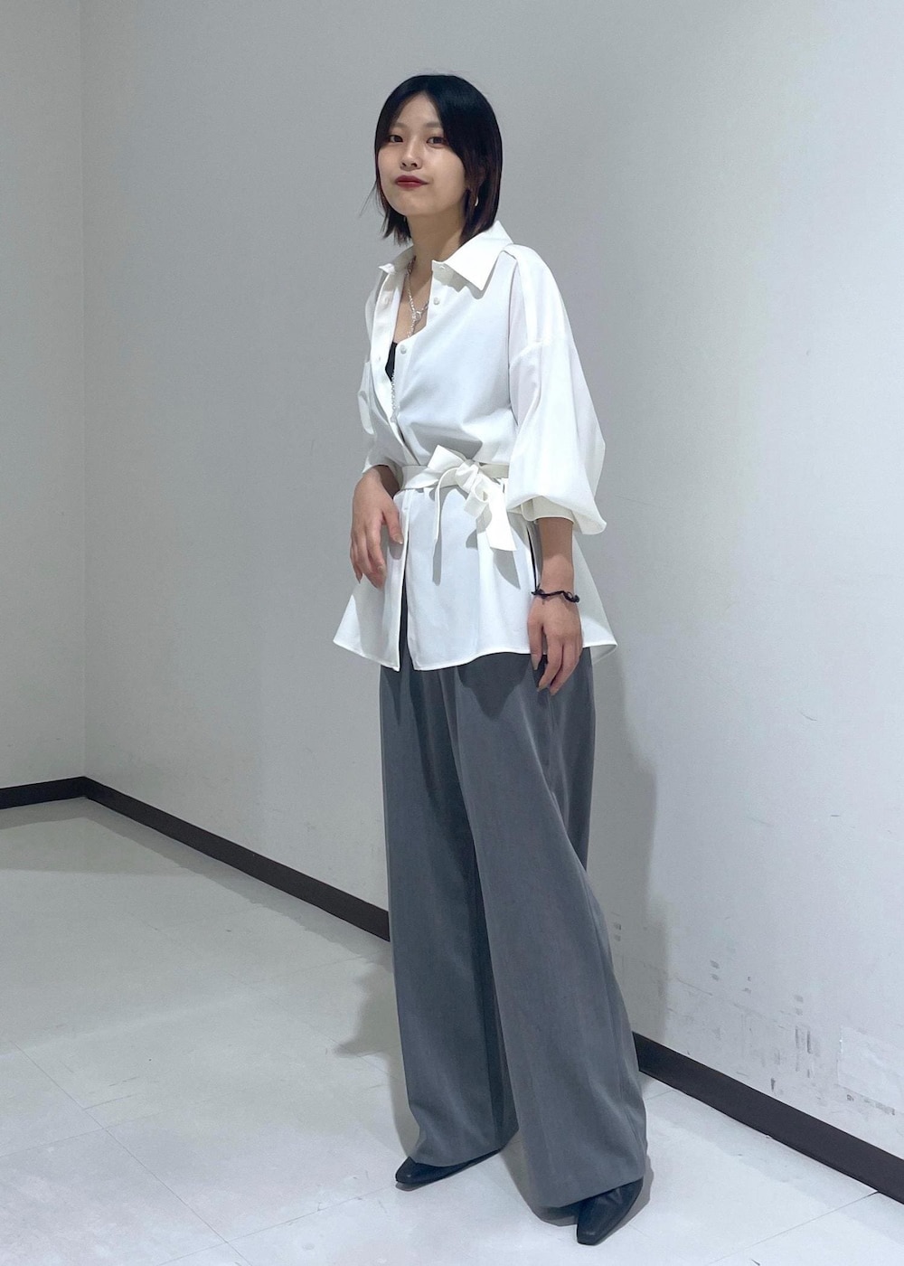 ホワイト系のシャツ/ブラウス、ホワイト系のショルダーバッグ、グレー系のスラックスを着用したレディースの夏コーディネートの2枚目の写真