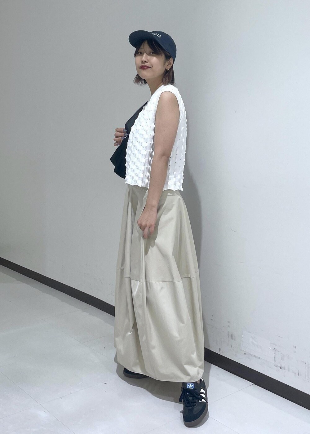 ベージュ系のスカート、ホワイト系のニット/セーター、ブルー系のキャップを着用したレディースの夏コーディネートの2枚目の写真