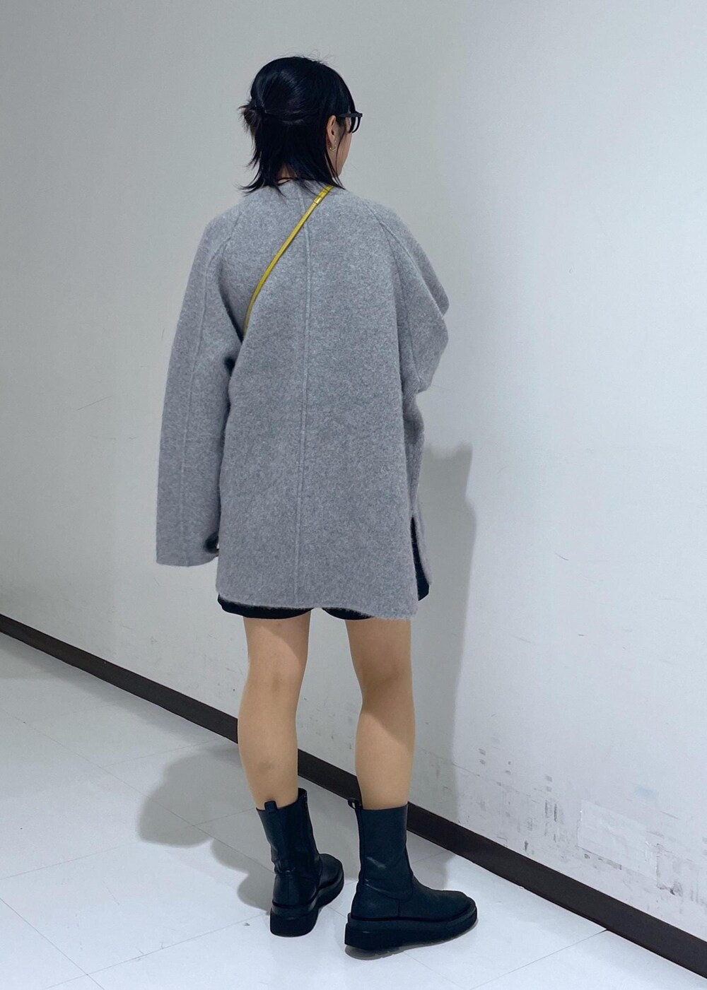 ブラック系のブーツ、グリーン系のニット/セーター、イエロー系のハンドバッグを着用したレディースの秋コーディネートの3枚目の写真