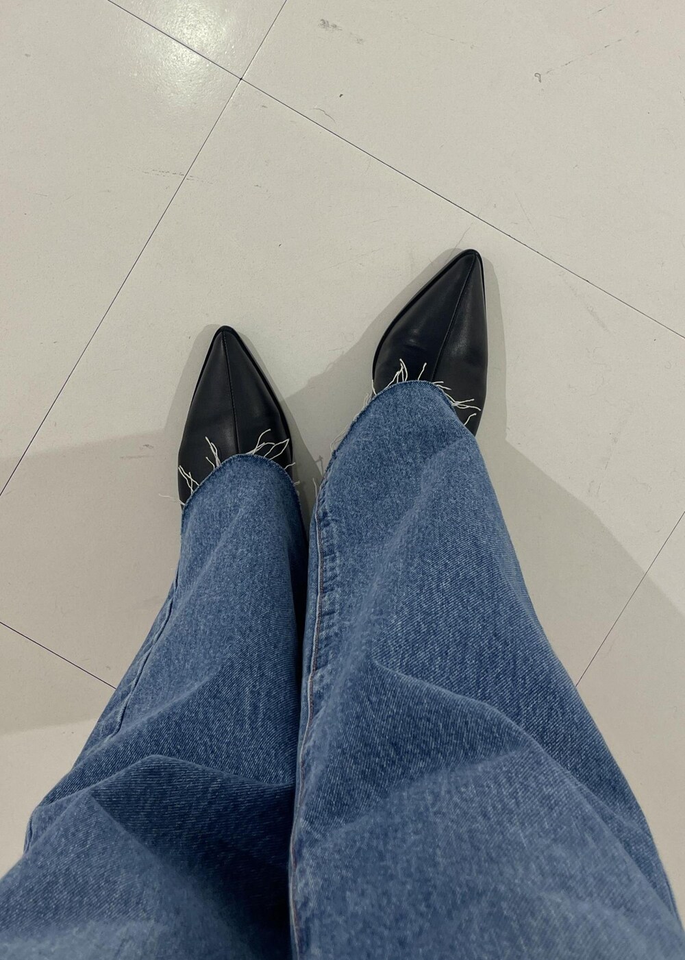 ブラック系のブーツ、ブルー系のデニムパンツ、ブラック系のハンドバッグを着用したレディースの秋コーディネートの5枚目の写真