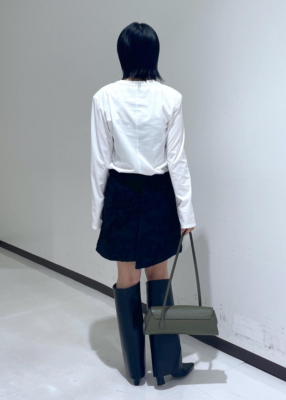 ブラック系のスカート、ブラック系のブーツ、ホワイト系のTシャツ/カットソーを着用したレディースの秋コーディネートの4枚目の写真