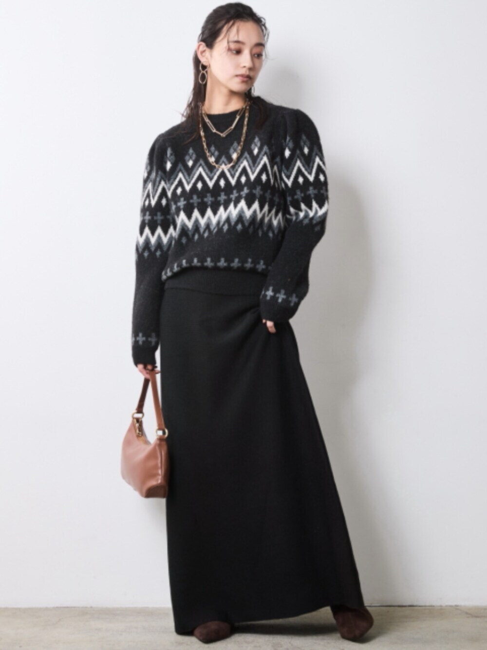 イエロー系のステンカラーコート、ブラック系のスカート、ブラック系のニット/セーターを着用したレディースの秋コーディネートの2枚目の写真