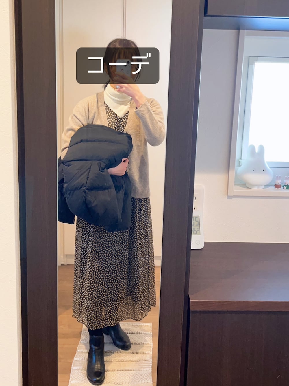 ブラック系のダウンジャケット/コート、ブラック系のワンピース、ブラック系のブーツを着用したレディースの冬コーディネートの2枚目の写真