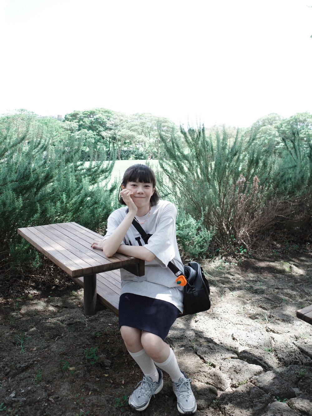 グレー系のTシャツ/カットソー、ブラック系のバッグ、シルバー系のスニーカーを着用したレディースの夏コーディネートの2枚目の写真