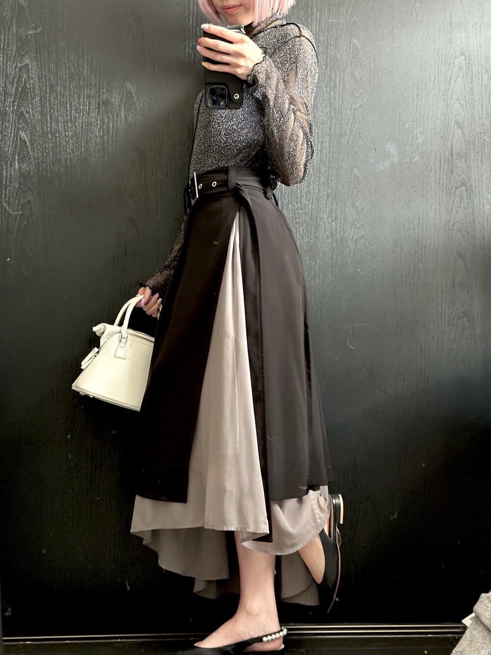 ブラック系のトップス、ブラック系のスカート、ホワイト系のハンドバッグを着用したレディースの夏コーディネートの2枚目の写真