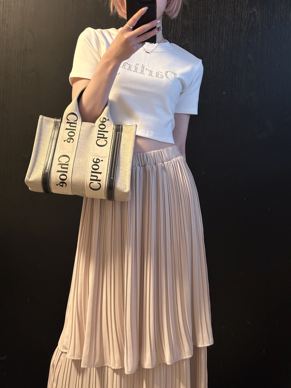 ホワイト系のTシャツ/カットソー、ホワイト系のスカート、ベージュ系のトートバッグを着用したレディースの夏コーディネートの2枚目の写真
