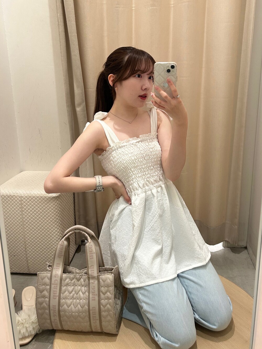 ベージュ系のショルダーバッグ、ホワイト系のキャミソール、ブルー系のデニムパンツを着用したレディースの夏コーディネートの2枚目の写真