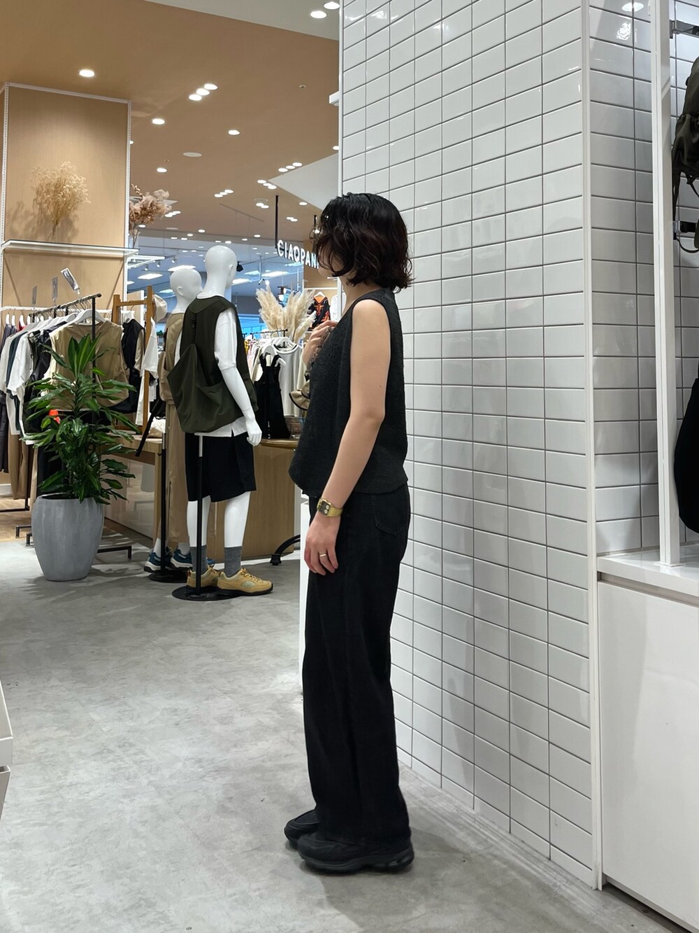 ブラック系のデニムパンツ、ブラック系のトートバッグ、グレー系のベストを着用したレディースの夏コーディネートの3枚目の写真