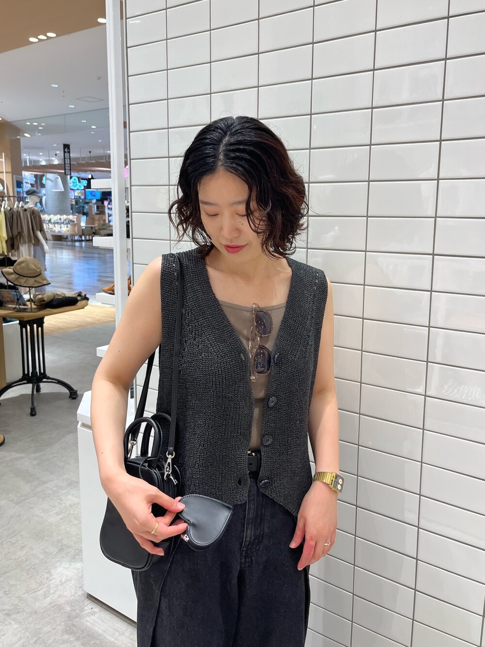 ブラック系のデニムパンツ、ブラック系のトートバッグ、グレー系のベストを着用したレディースの夏コーディネートの5枚目の写真