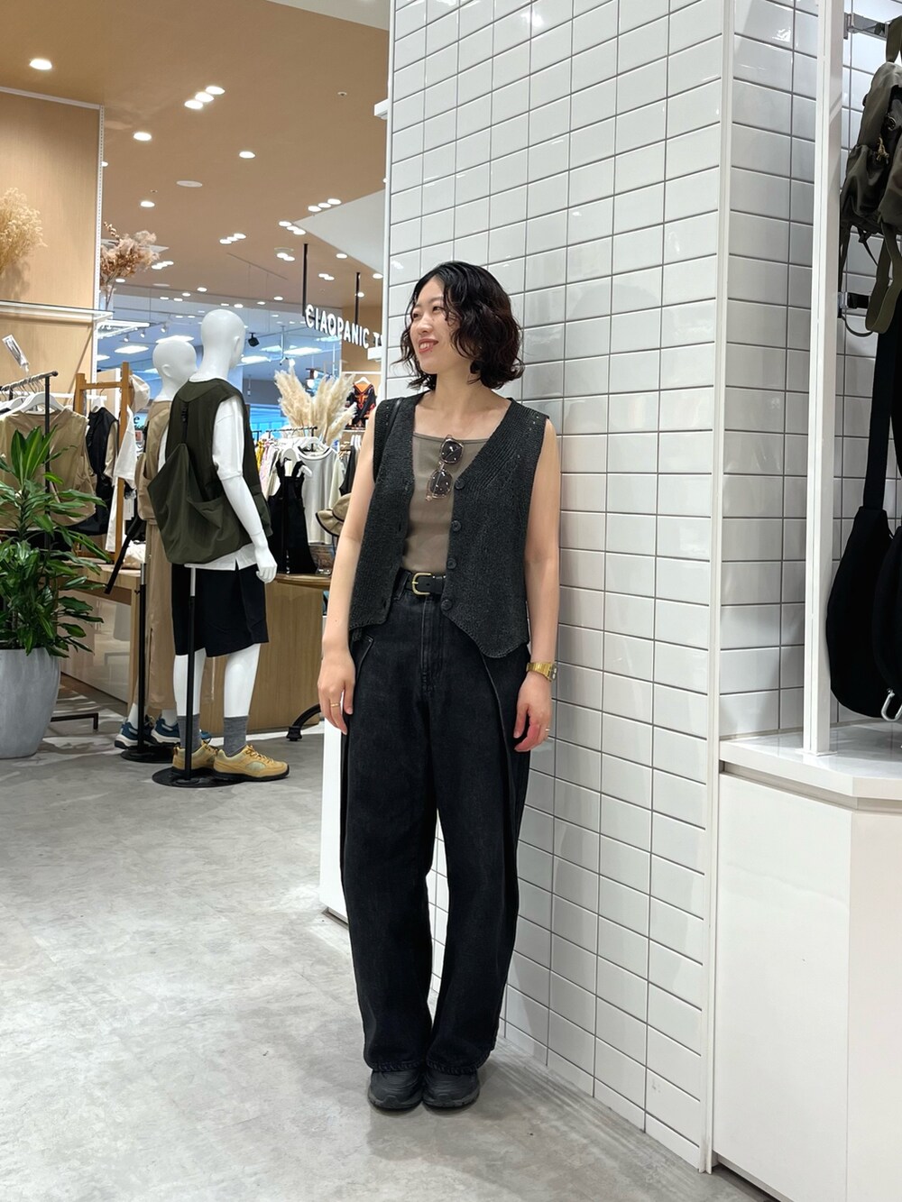 ブラック系のデニムパンツ、ブラック系のトートバッグ、グレー系のベストを着用したレディースの夏コーディネートの2枚目の写真