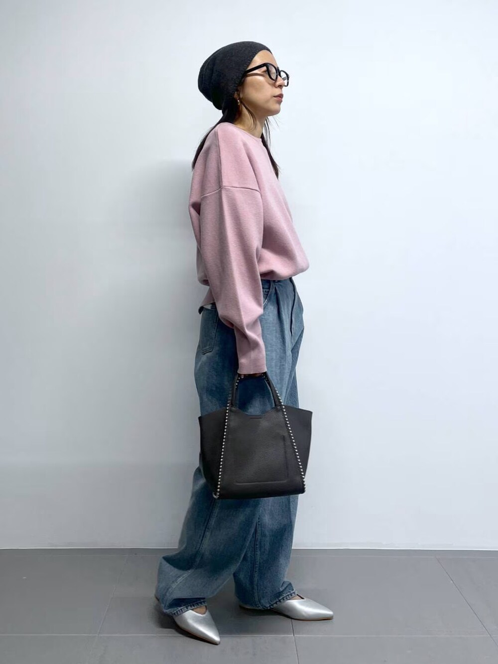 ピンク系のニット/セーター、ブルー系のデニムパンツ、グレー系のトートバッグを着用したレディースの春コーディネートの2枚目の写真