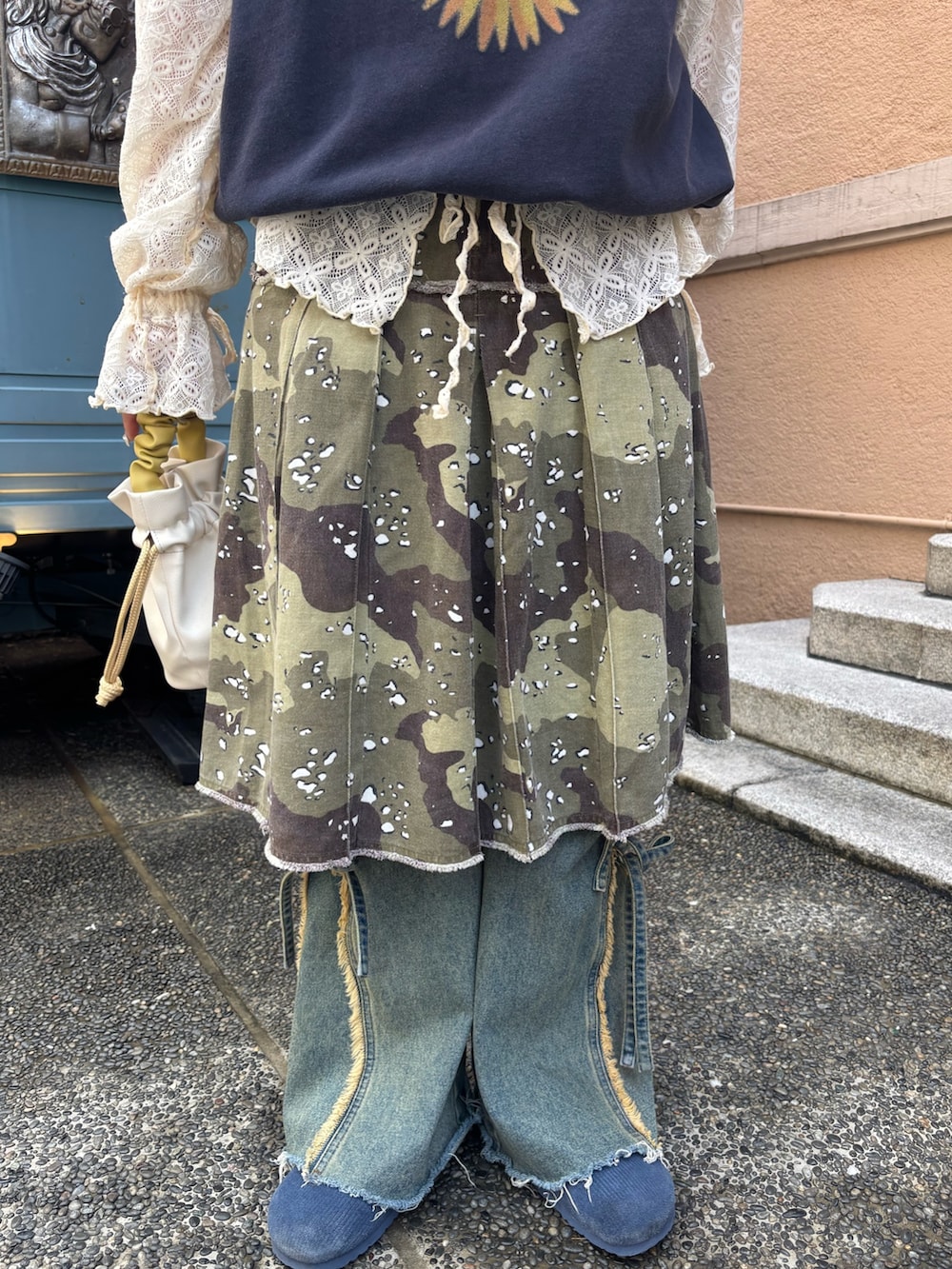 ブルー系のトップス、ベージュ系のスカート、ベージュ系のデニムパンツを着用したレディースの春コーディネートの4枚目の写真