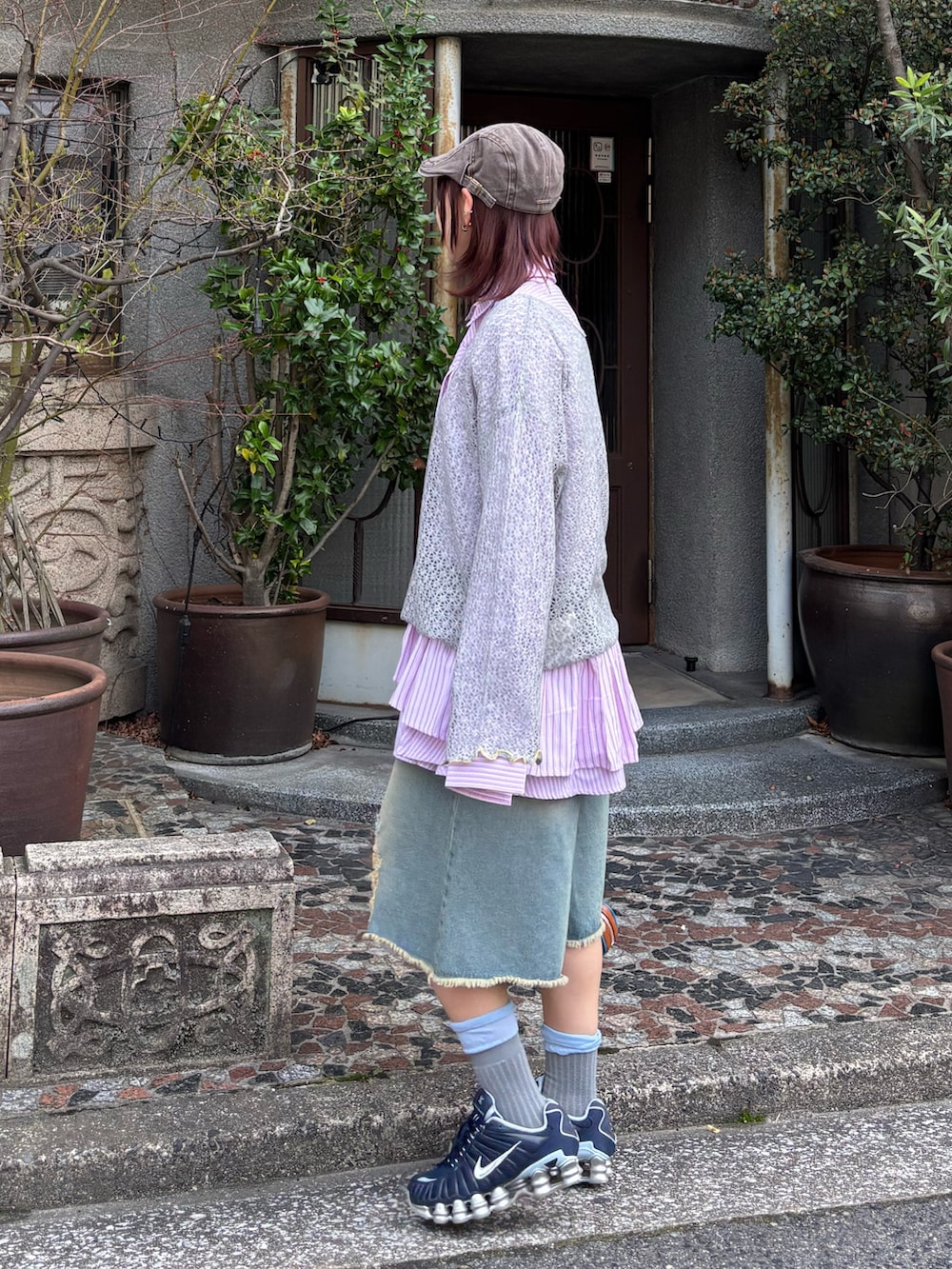 グレー系のニット/セーター、ピンク系のシャツ/ブラウス、ブルー系のデニムパンツを着用したレディースの春コーディネートの2枚目の写真